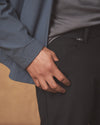 Person wearing a gray jacket and black pants with a blurred background