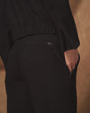 Person wearing a black outfit with a brand logo on a brown background