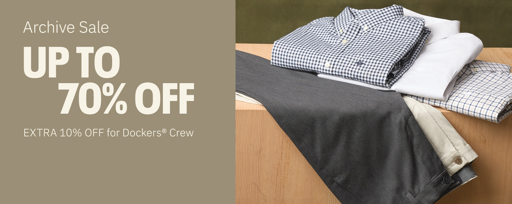Clothing sale banner with folded shirts and pants on a wooden surface, featuring text about discounts.