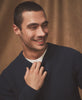 Man wearing a dark blue sweater against a brown background