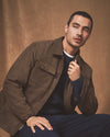 Man wearing a brown jacket sitting against a brown background