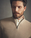 Man wearing a beige sweater with a neutral background