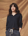 Woman wearing a dark blue shirt and striped pants against a brown background
