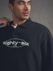 Man wearing a navy blue polo shirt with 'eighty-six' logo on a gray background