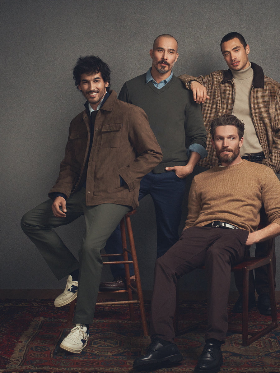 Four men posing together against a gray background