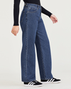 Side view of model wearing Medium Indigo Stonewash Women's Relaxed Fit Mid-Rise Jeans.