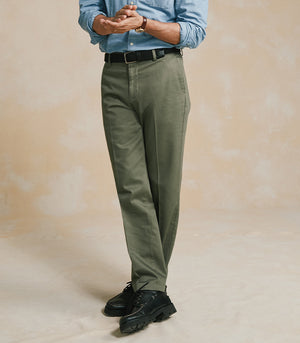 Man wearing a blue shirt and green pants against a beige background