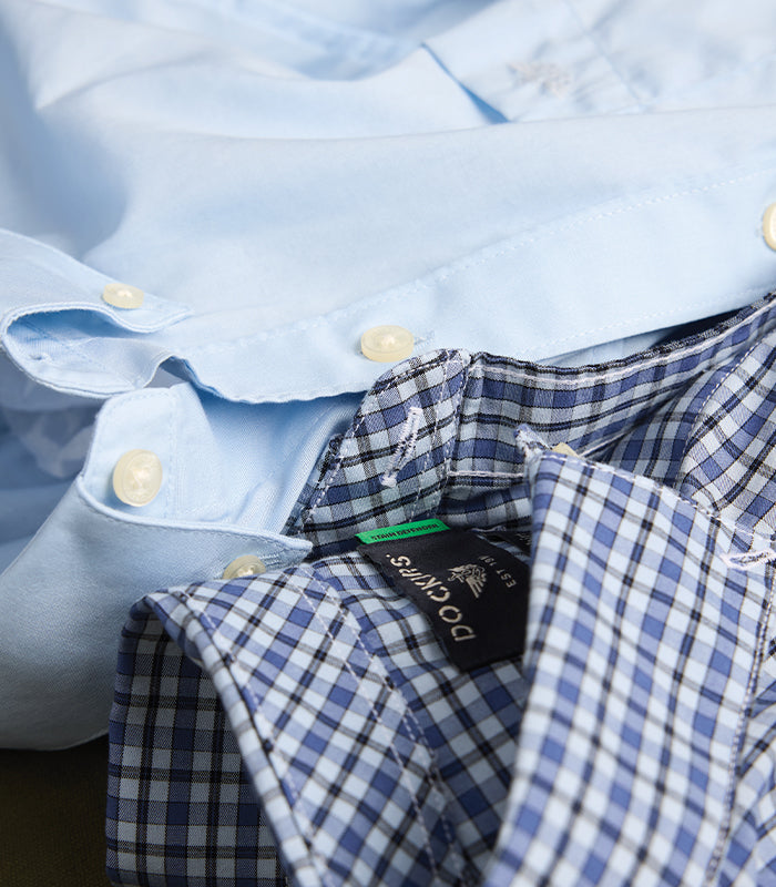 Close-up of a light blue shirt with a checkered inside lining, featuring a Doppio brand tag.