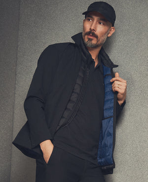 Man wearing a black jacket with a blue lining against a gray background
